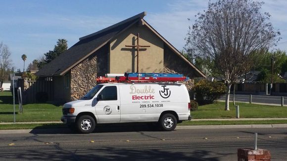 A double electric van is parked in front of a church A double electric van is parked in front of a church