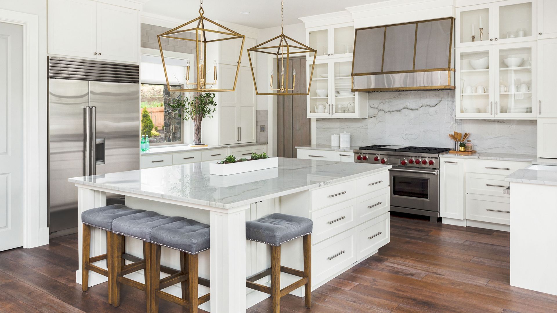 Bright modern kitchen with white cabinets, island, stainless steel appliances, and gray stools
