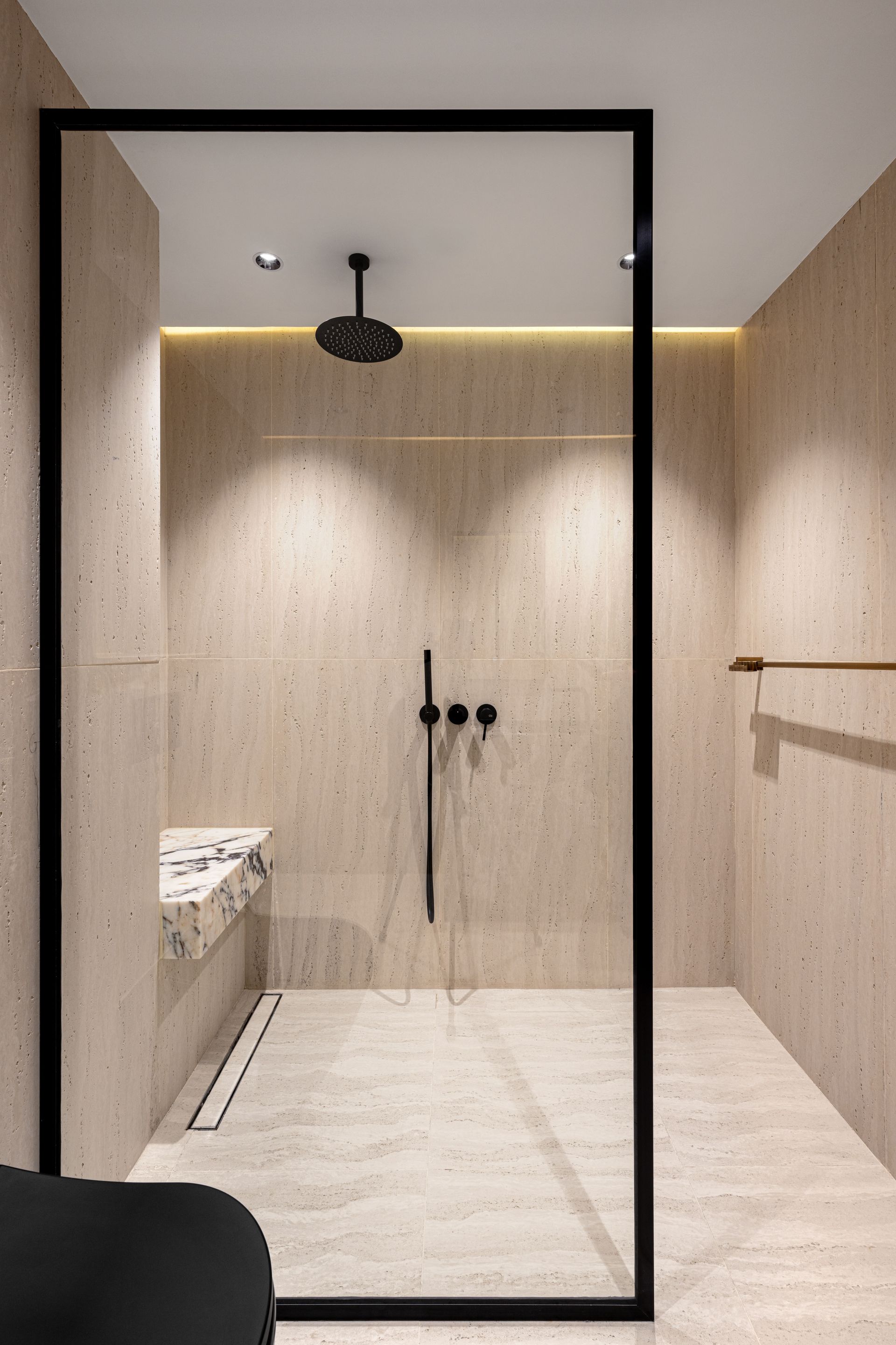 Modern glass shower with white marble-look tile, built-in shelves, and a sliding door in a bright bathroom