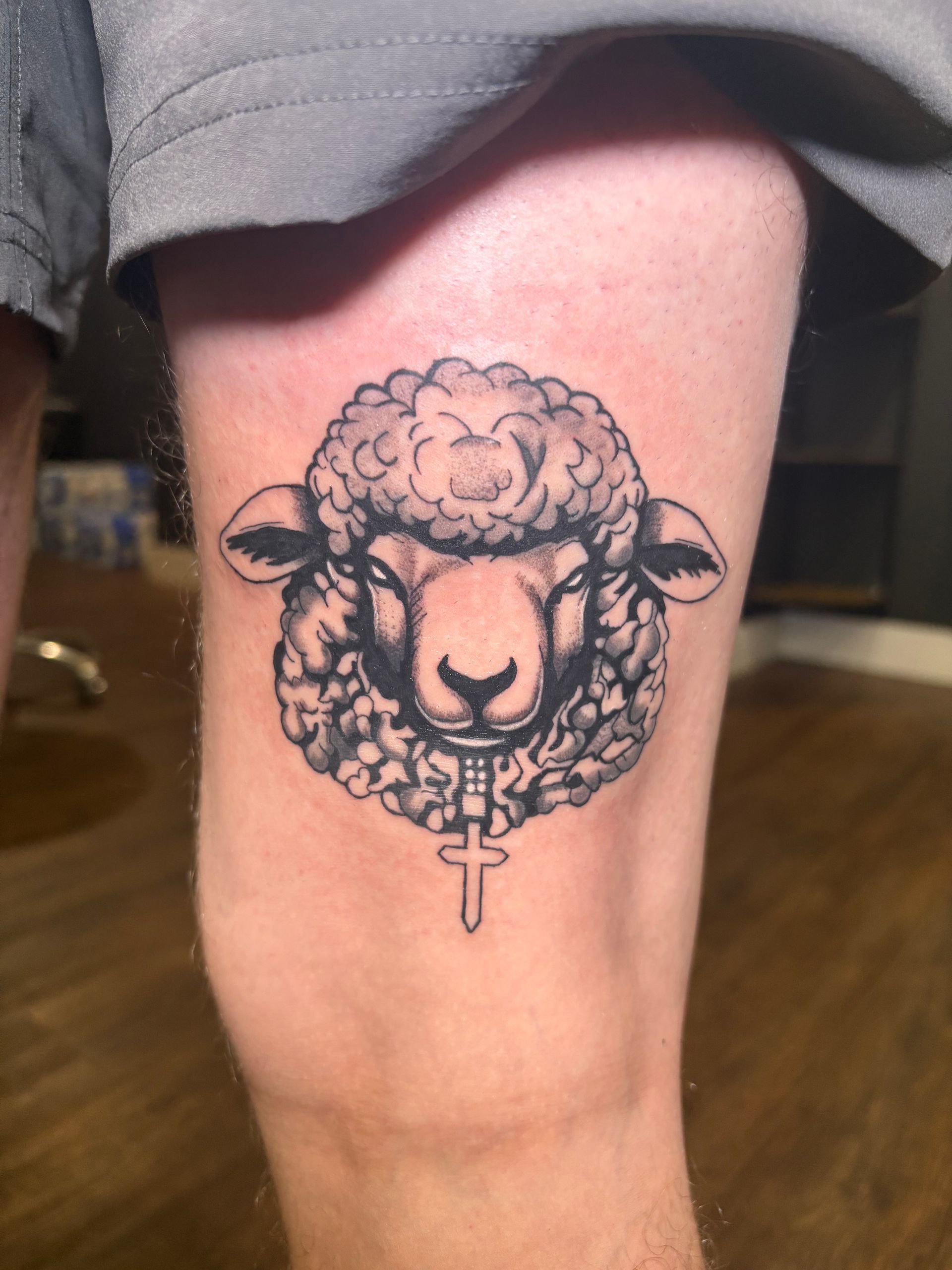 Close-up of a sheep tattoo on a person’s thigh, black ink on light skin.