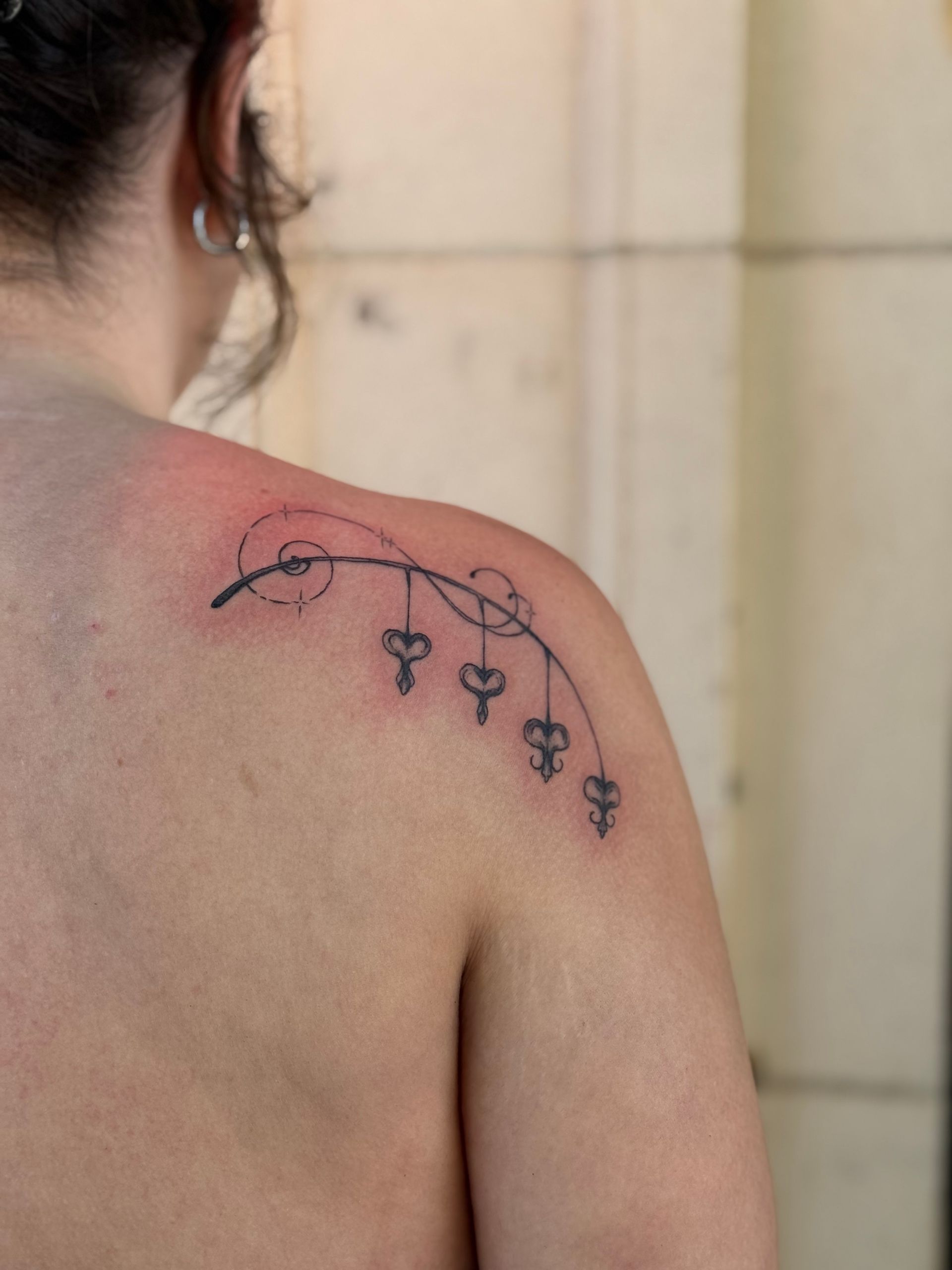 Upper back with a black floral tattoo curving over the shoulder blade.