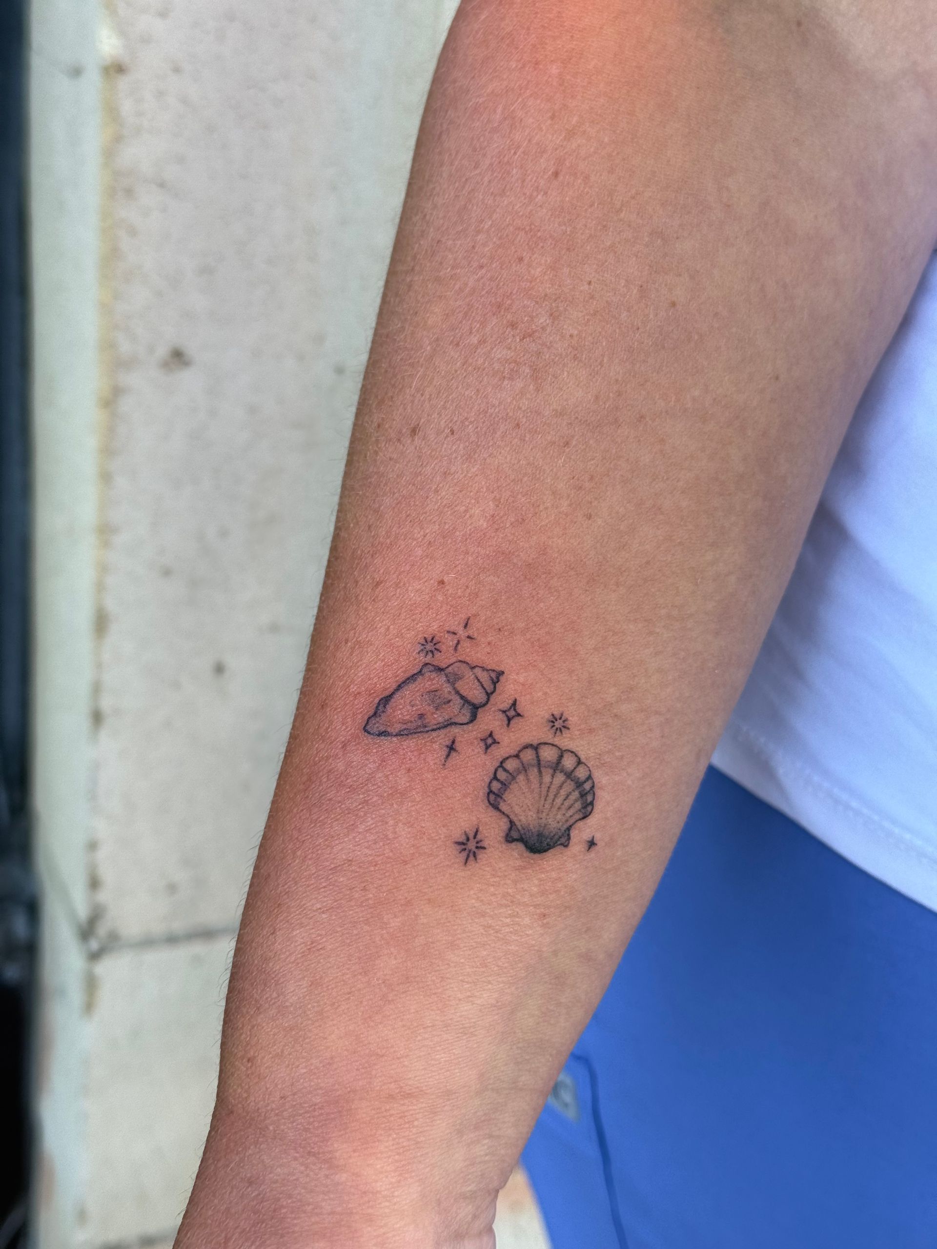 Close-up of an arm with two small black tattoo-like symbols on the forearm