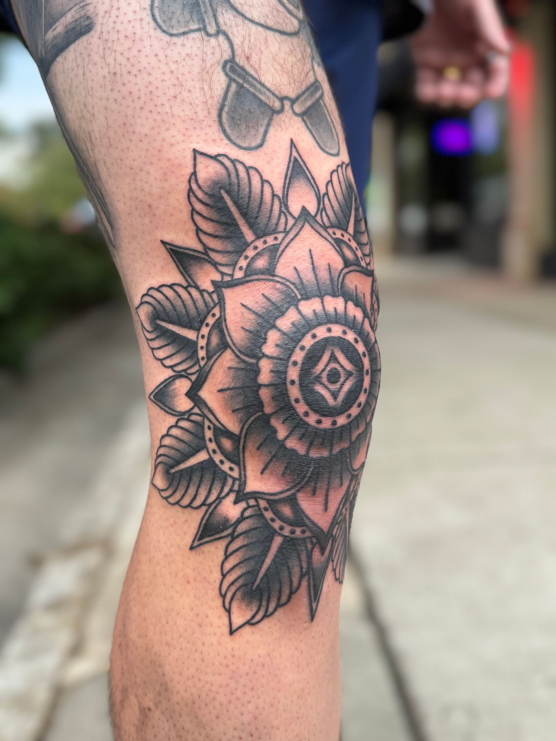 Close-up of a black floral mandala tattoo on a person’s leg outdoors