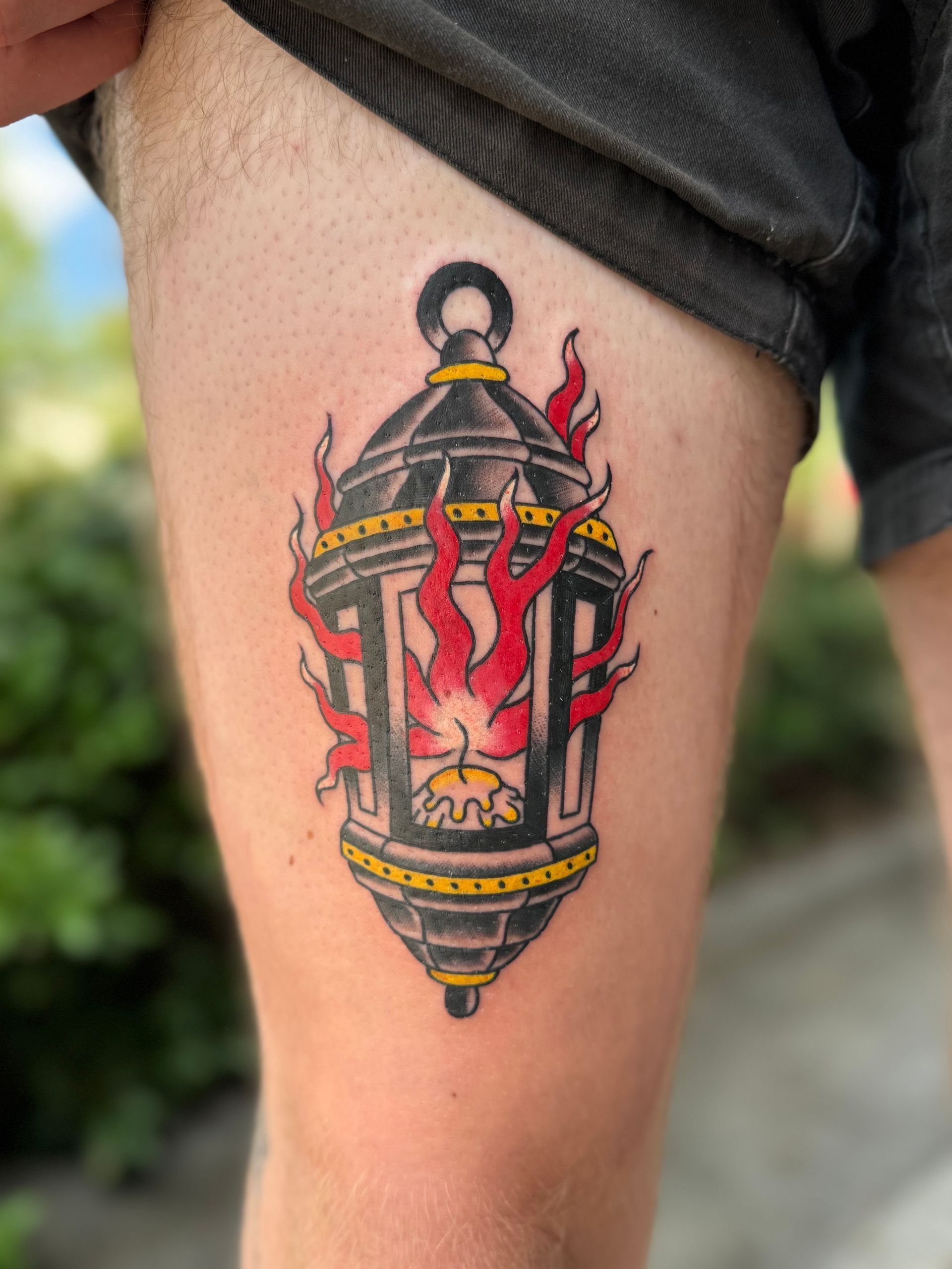 Colorful lantern tattoo with red flames on a person’s upper arm