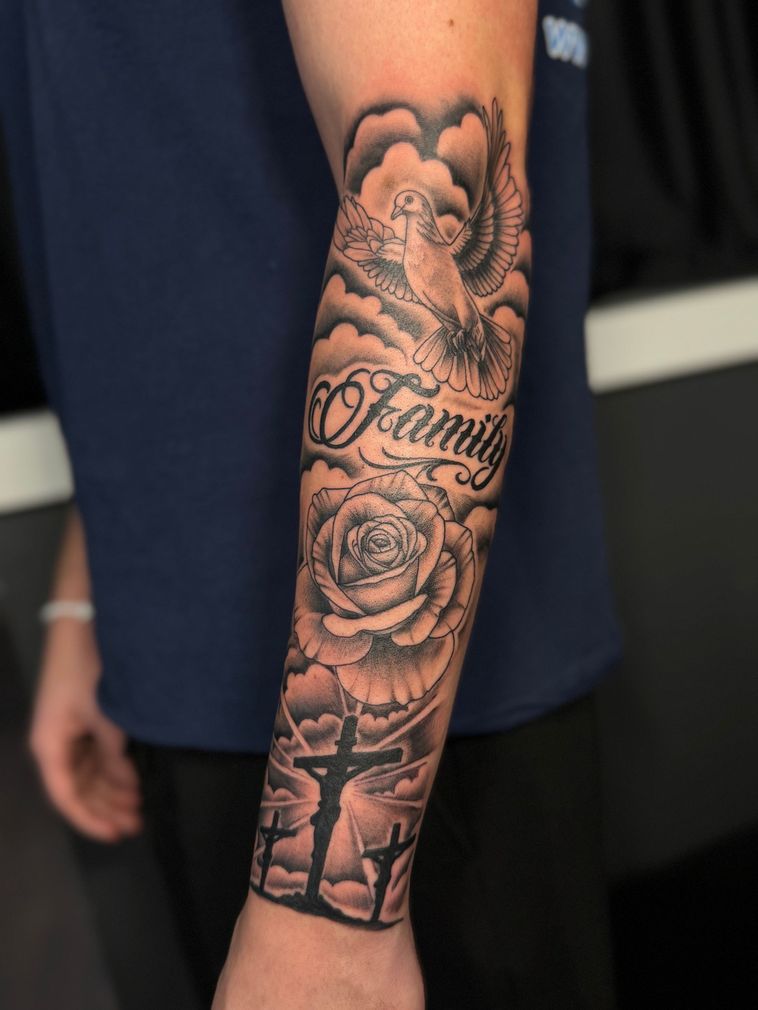 Tattooed forearm with black-and-gray roses and script design