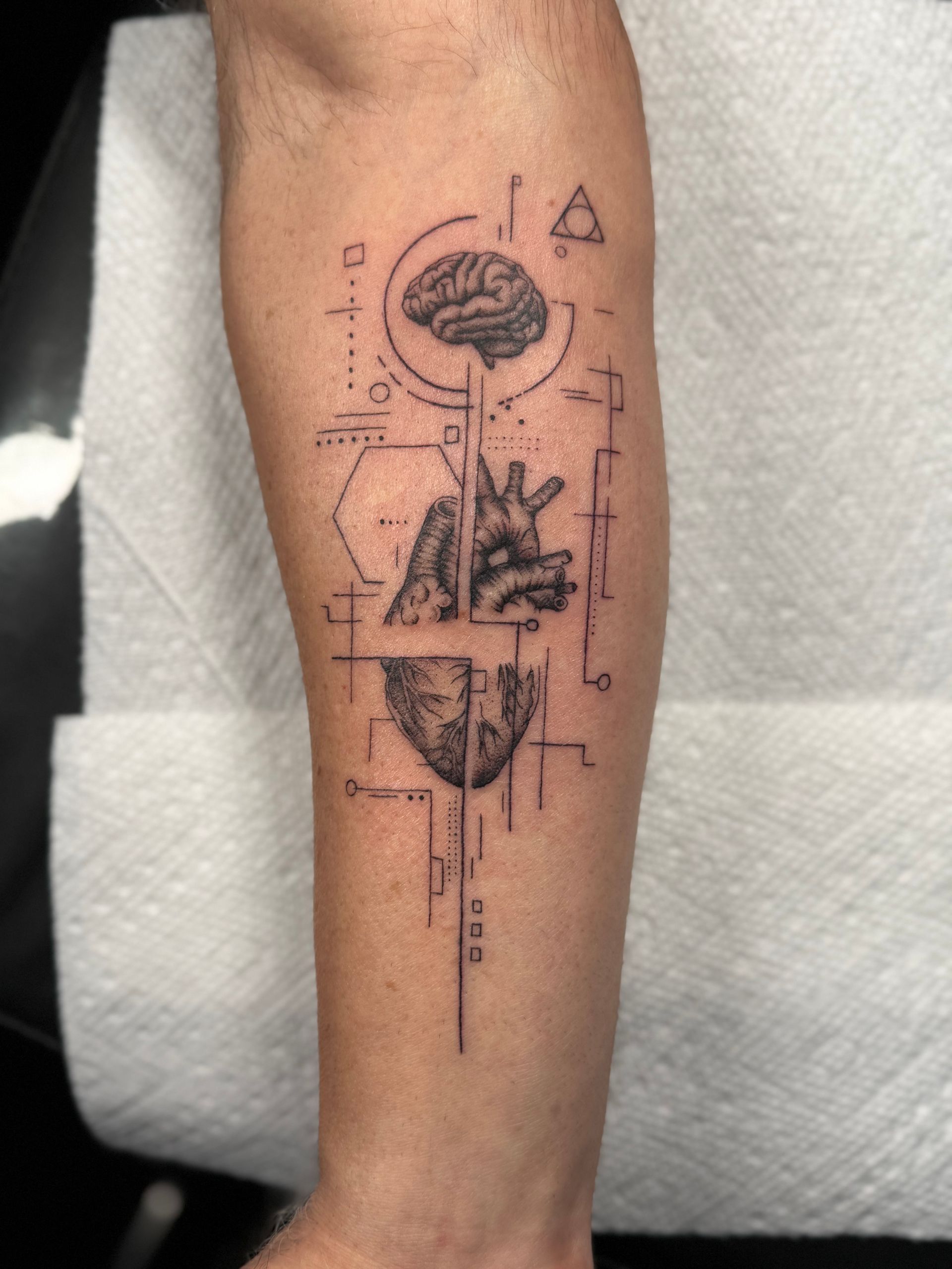 Forearm with a geometric black tattoo featuring a flower-like design and abstract lines