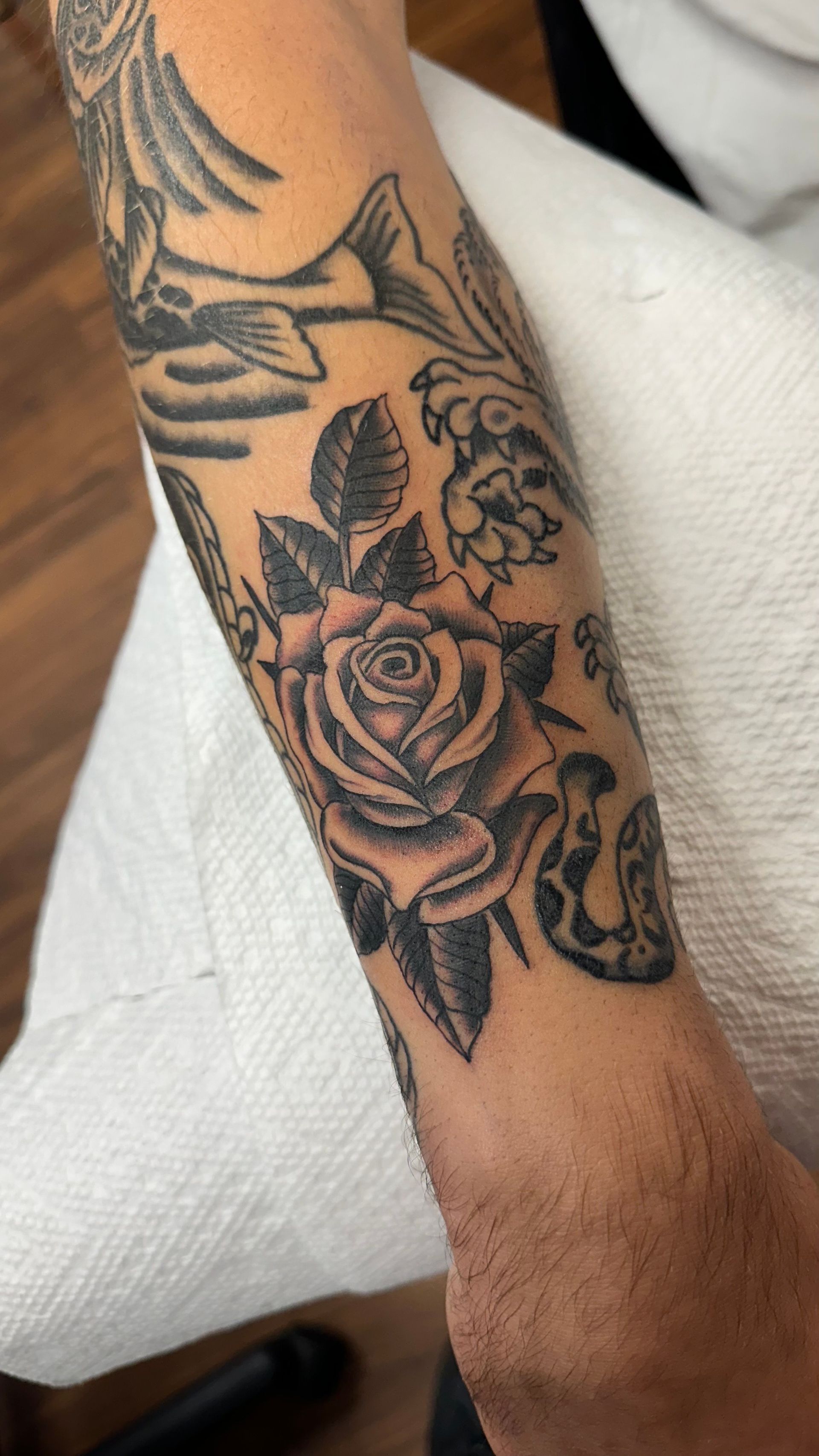 Black floral tattoo sleeve on a forearm resting on a white surface