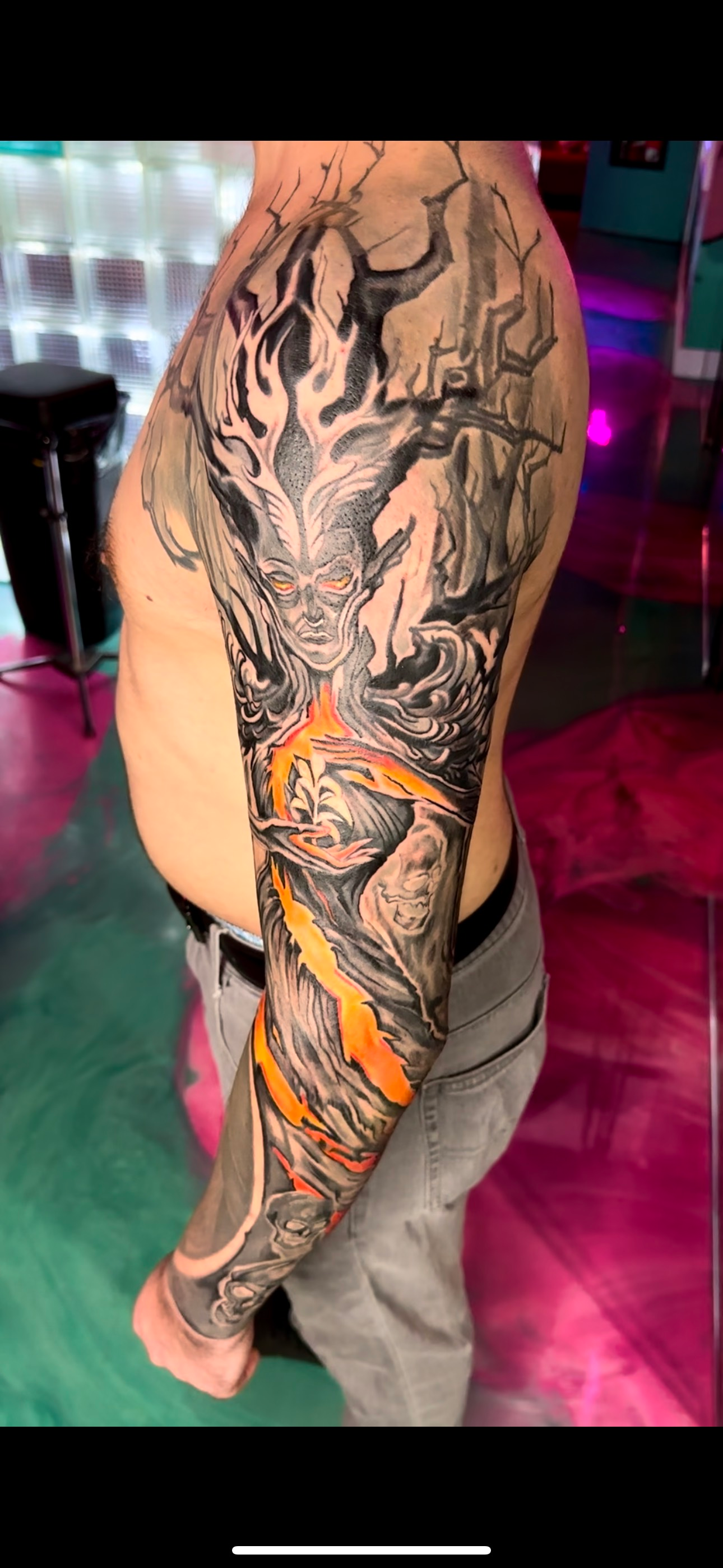 Arm tattoo sleeve with intricate black and orange dragon artwork on a person’s arm and shoulder