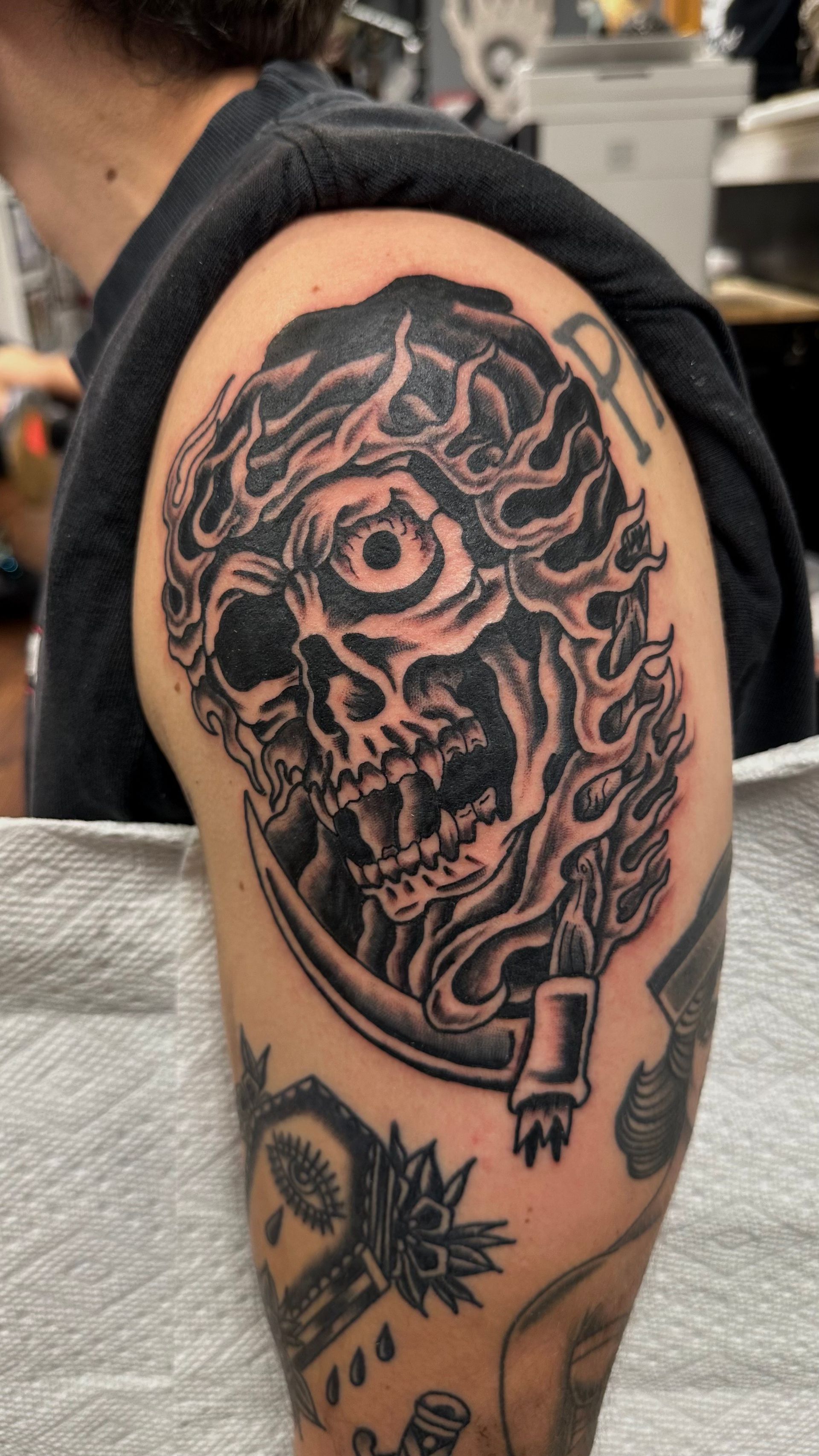 Arm tattoo of a skull with swirling smoke and a rose, on a person’s upper arm