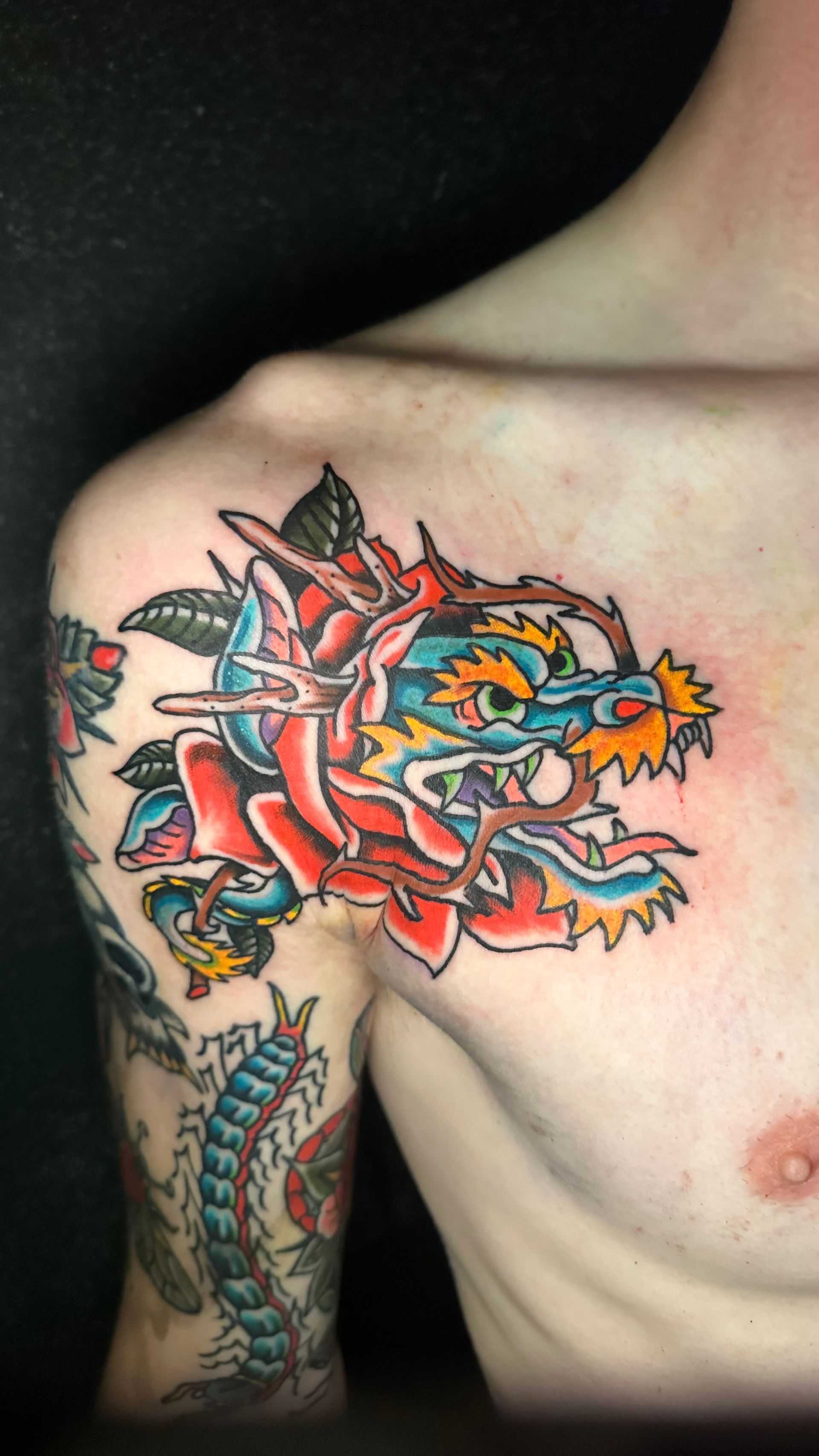 Close-up of a colorful dragon tattoo on a person’s shoulder and upper arm