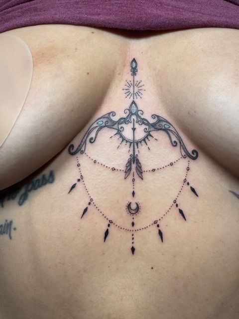 Intricate black ornamental tattoo across the upper chest and sternum on skin