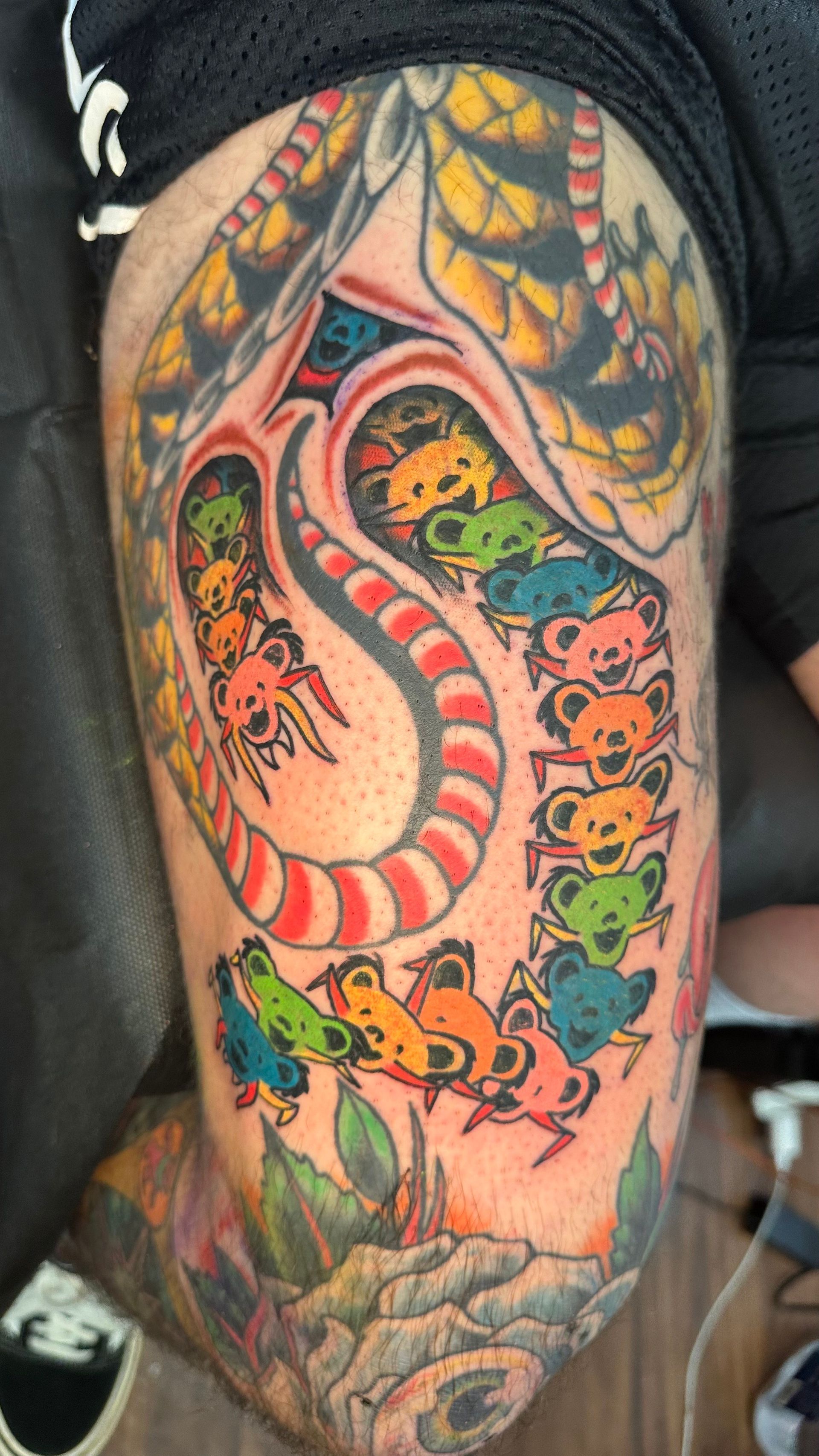 Colorful snake tattoo with orange, red, blue, and black details on a forearm.