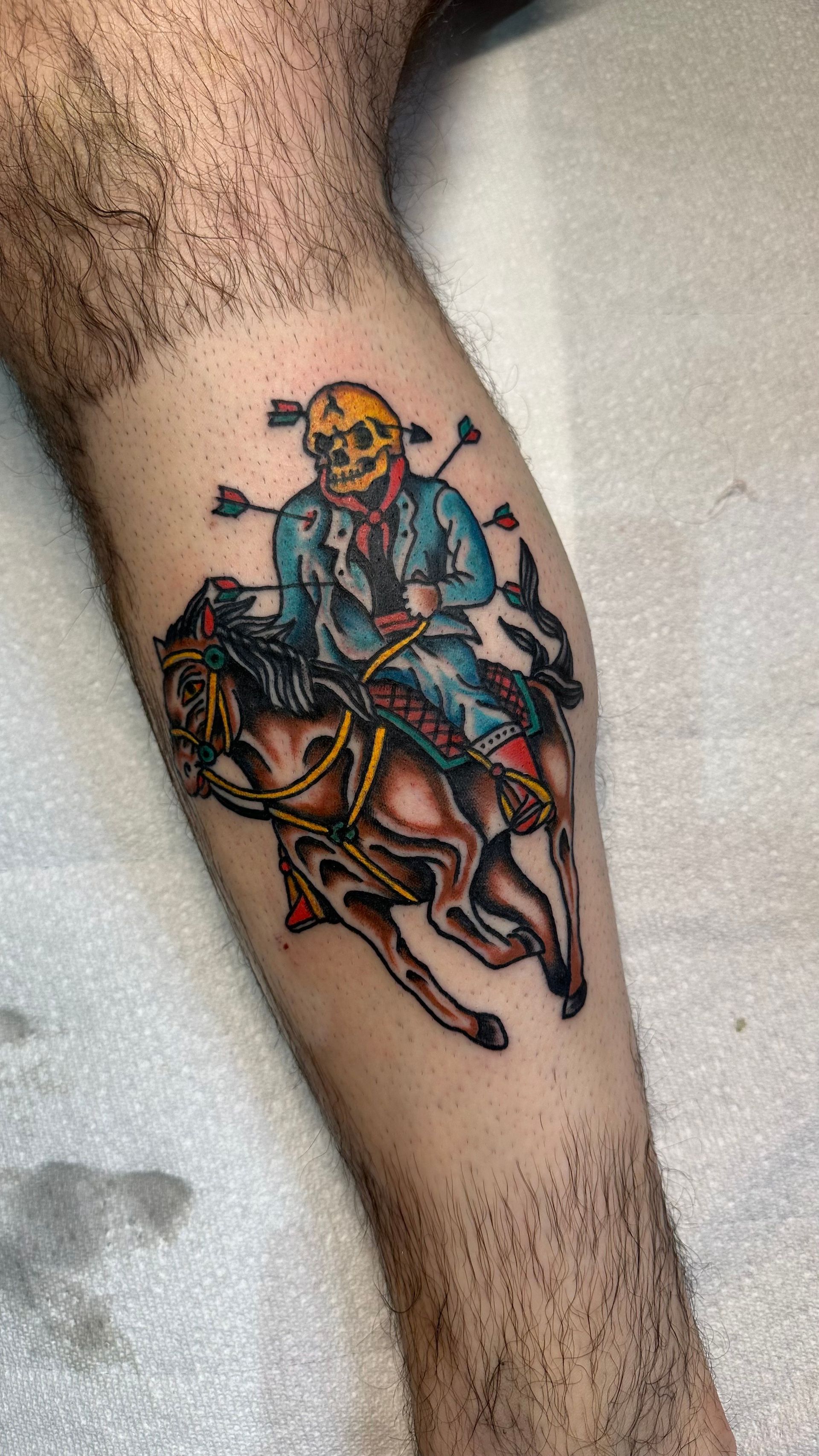 Colorful tattoo of a skeleton rider on a galloping horse on a lower leg