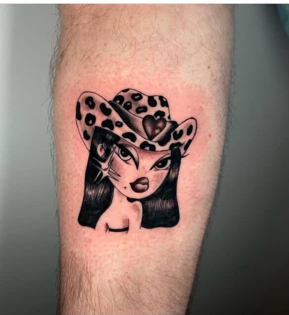 Black-and-white tattoo of a cartoon girl with a spotted bow on a forearm