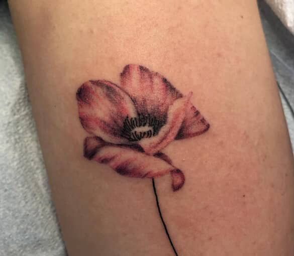 Pink flower tattoo on skin with a thin black stem