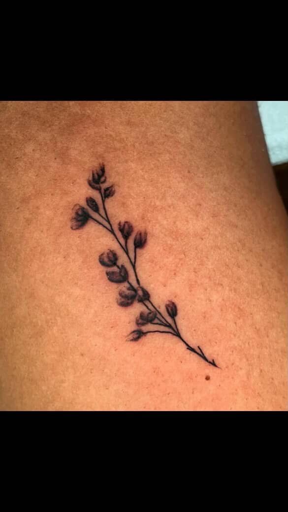 Small black vine tattoo on skin with leaves and berries.