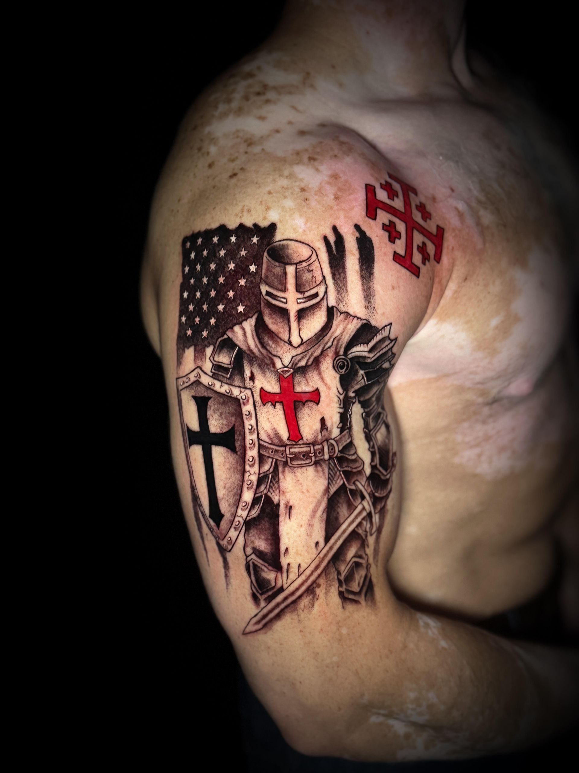 Arm tattoo of a medieval knight with a cross, set against an American flag background
