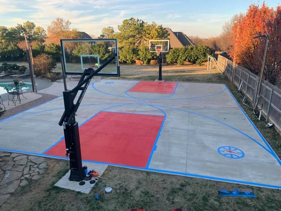 A basketball court is being painted red and blue in a backyard.