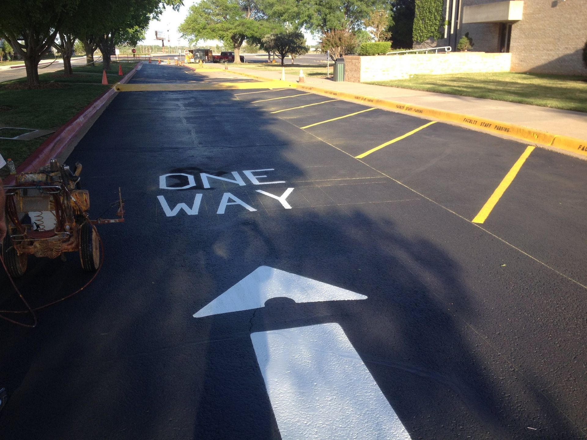 A one way sign is painted on the side of a road