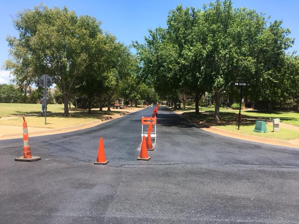 A row of orange cones are lined up on the side of a road