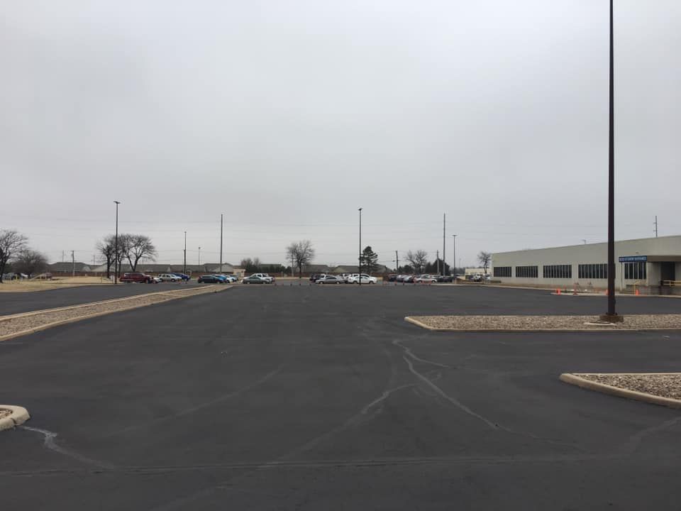 A parking lot with cars parked in front of a building on a cloudy day.