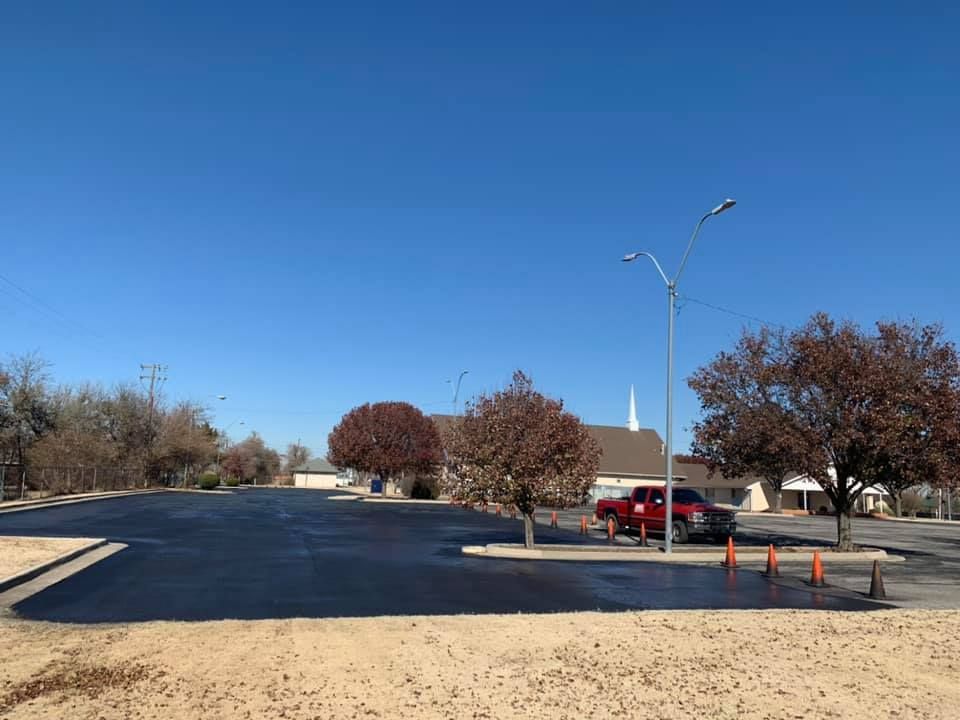 A red truck is parked in a parking lot next to a church.