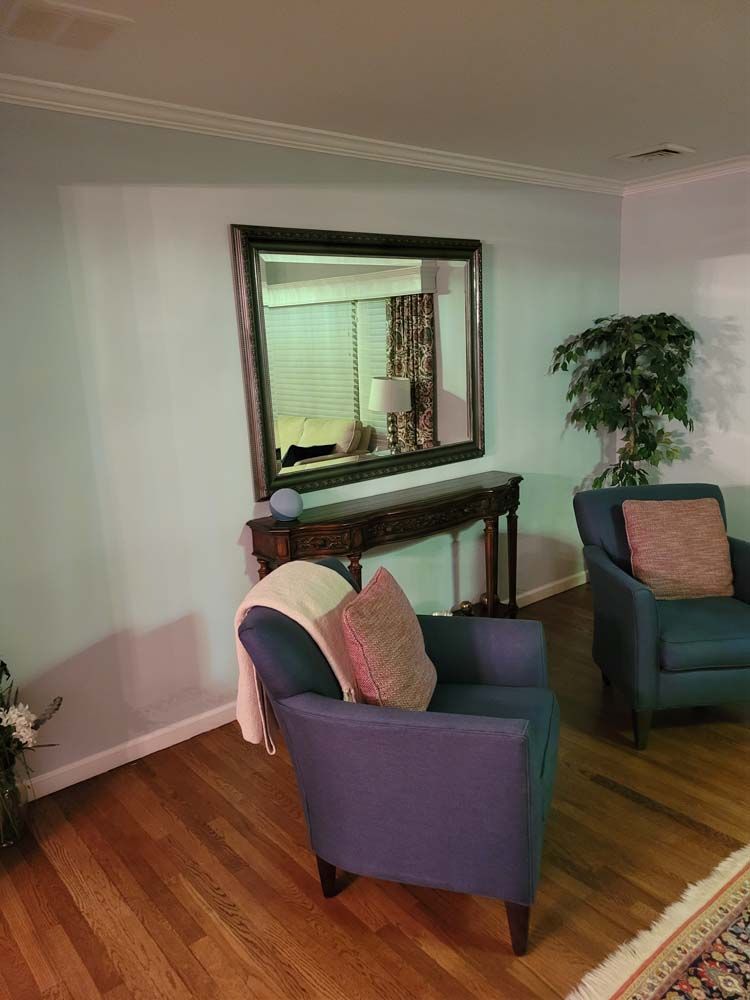 Living room with blue armchairs, a mirror, and a console table.