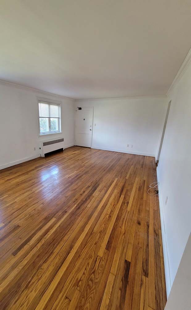 Empty room with wood flooring, white walls, and a door and window.
