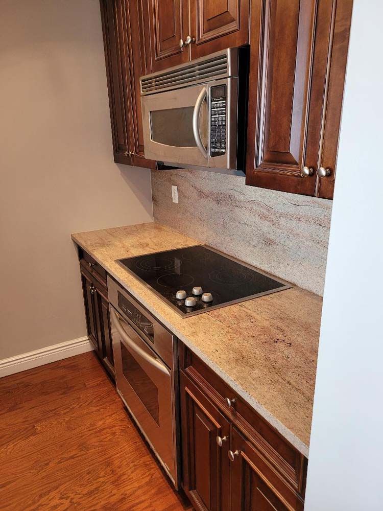 Small kitchen with dark wood cabinets, stainless steel appliances, and beige countertops.