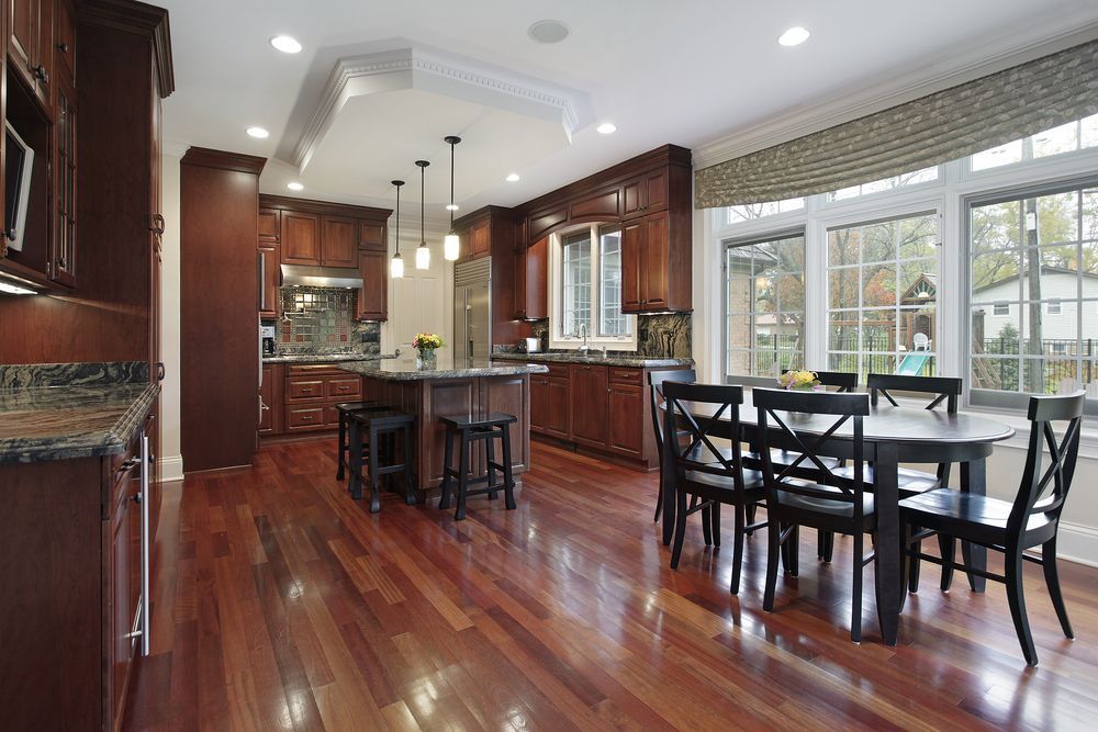 A kitchen and dining room in a house with hardwood floors and stainless steel appliances.