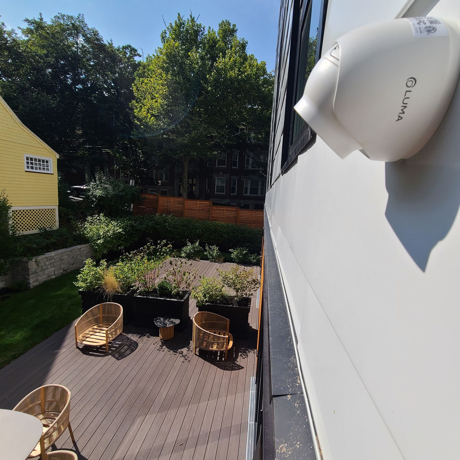 Outdoor patio with speakers, TV, and greenery.