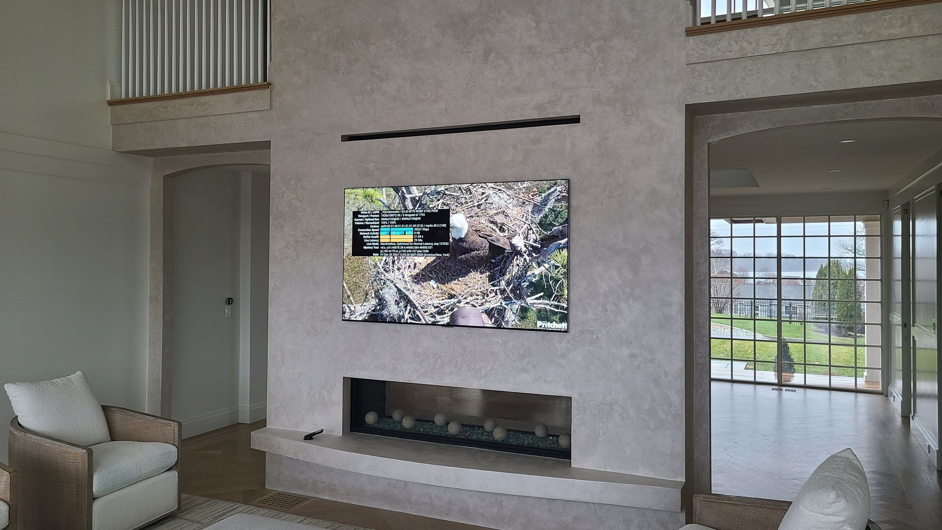Modern living room with a large fireplace, TV, and seating; neutral colors.