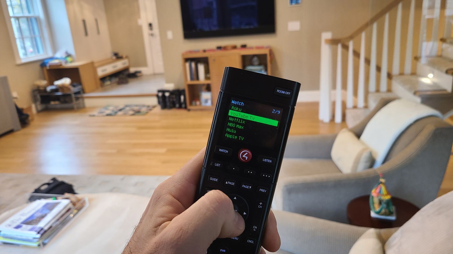 A level on top of a touchscreen, hand touching volume control. Music playing on screen, kitchen setting.