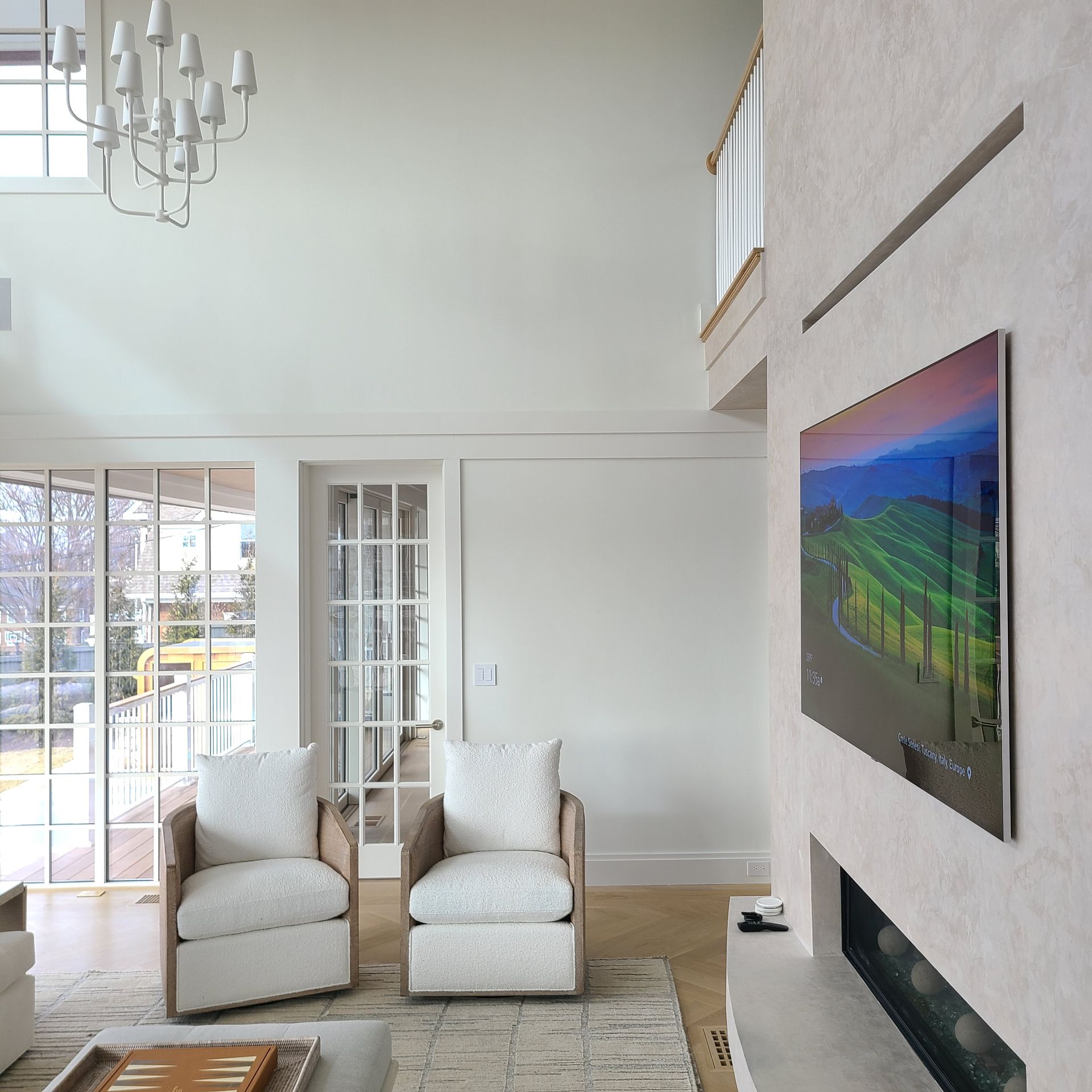 Living room with white walls, two chairs, artwork, and fireplace.