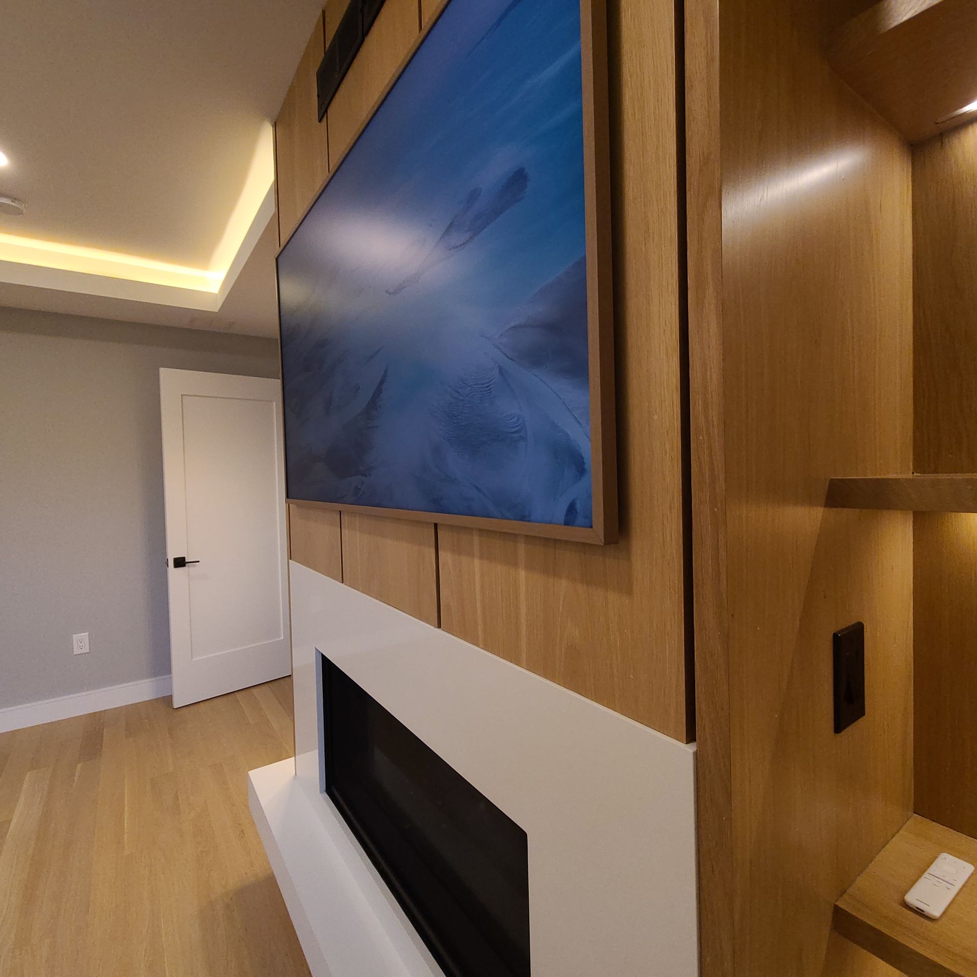 Large TV above a white fireplace, set in a wood-paneled wall with an alcove.