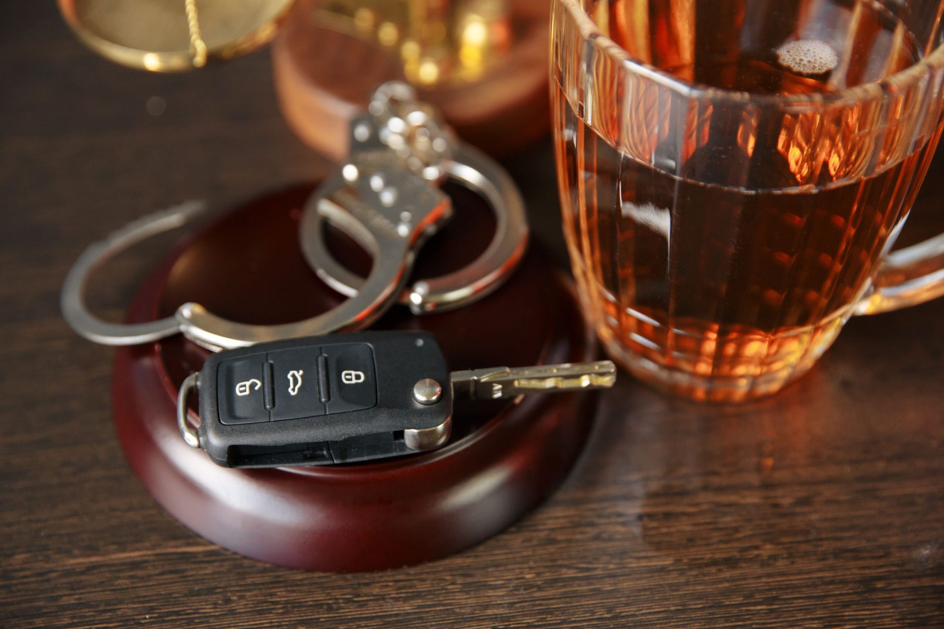 Car key fob and keyring beside a glass of amber drink on a wooden table