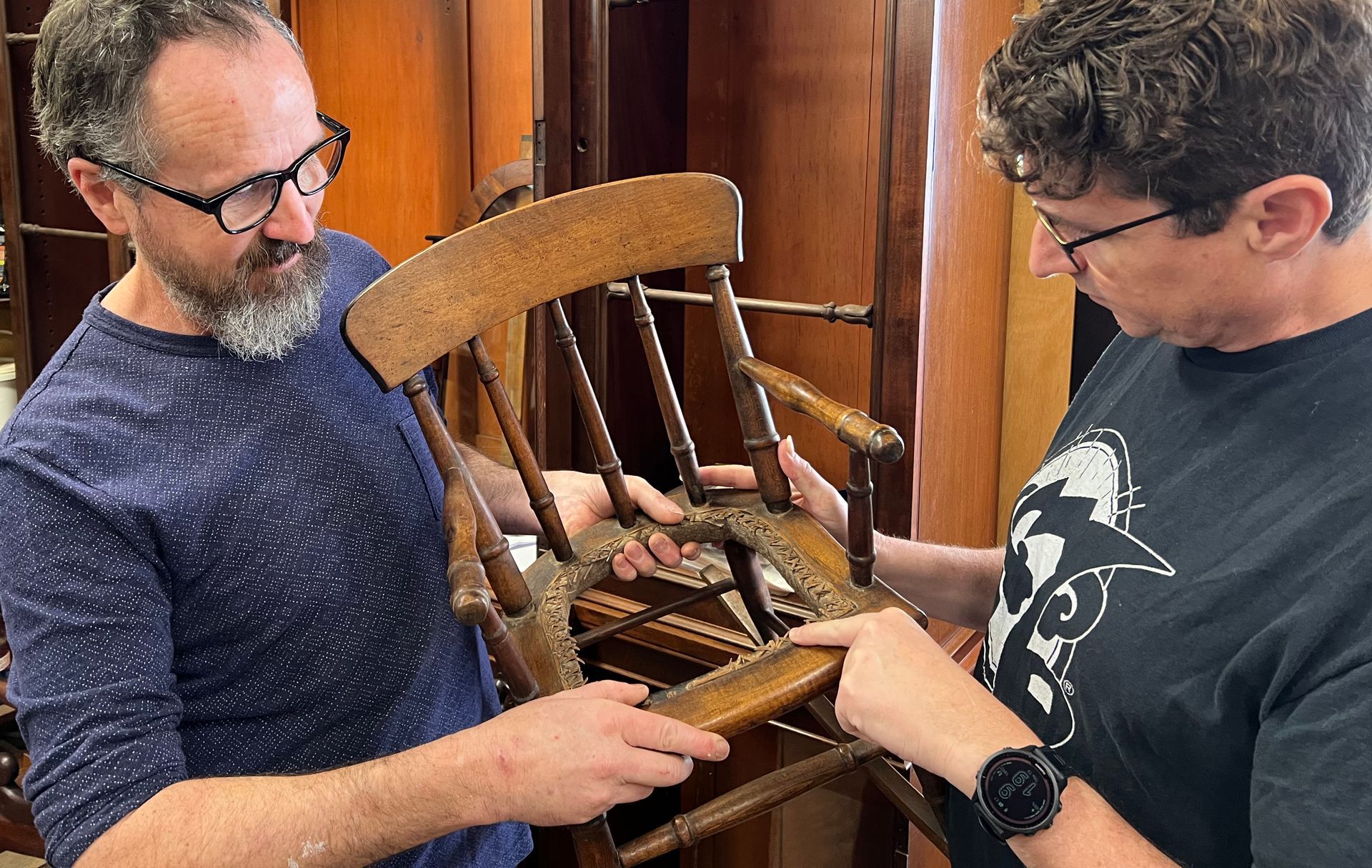 Frank and customer looking at an antique wooden chair which needs to be repaired.