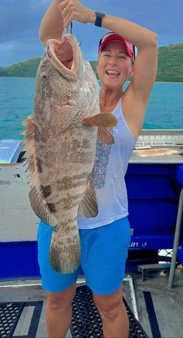 A Woman is Holding a Large Fish in Her — Whitsunday Fishing Charters In Airlie Beach, QLD