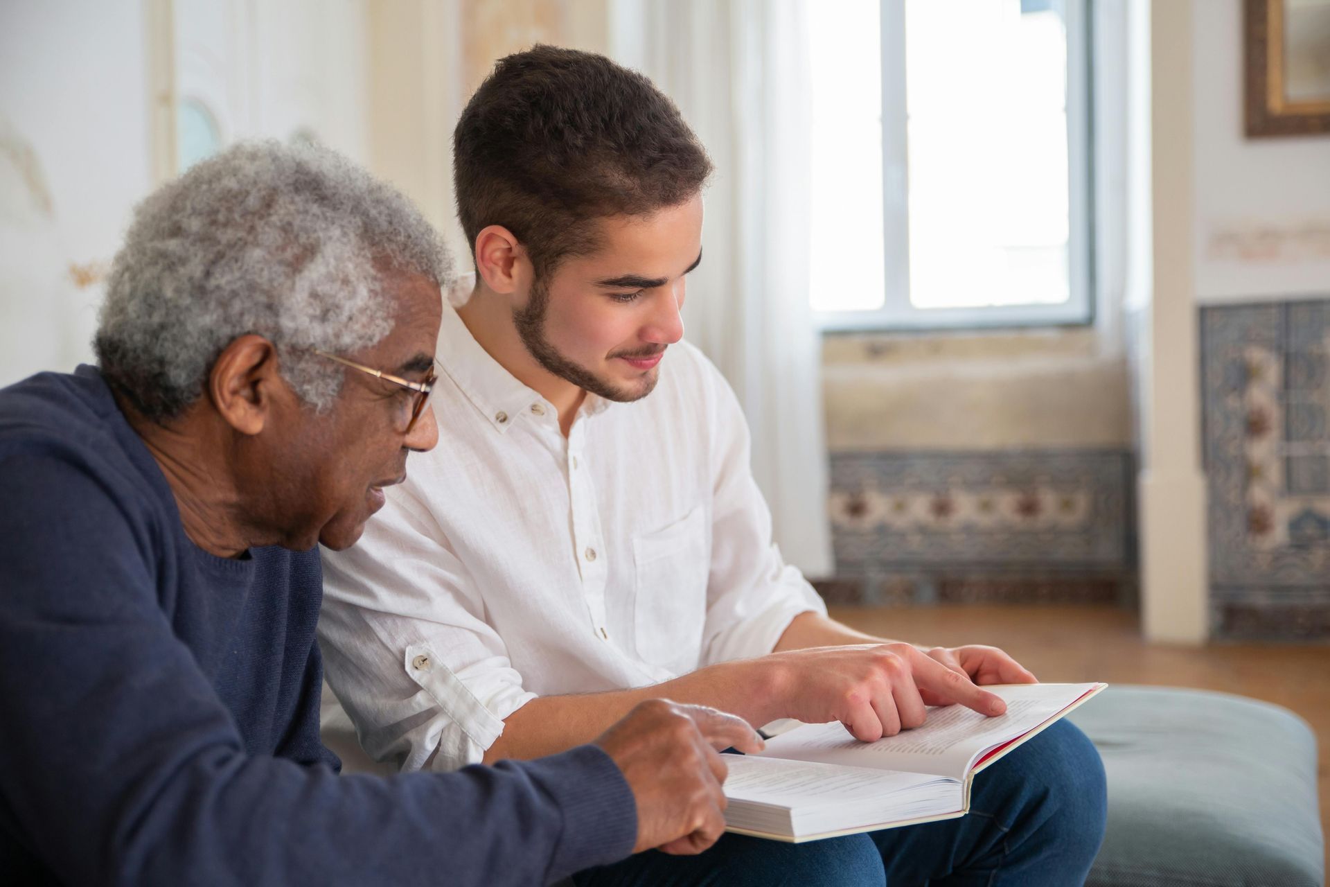 Two men in a classroom. One is holding a book.