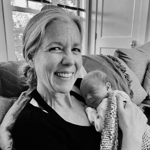 Smiling doula holding newborn baby in home setting