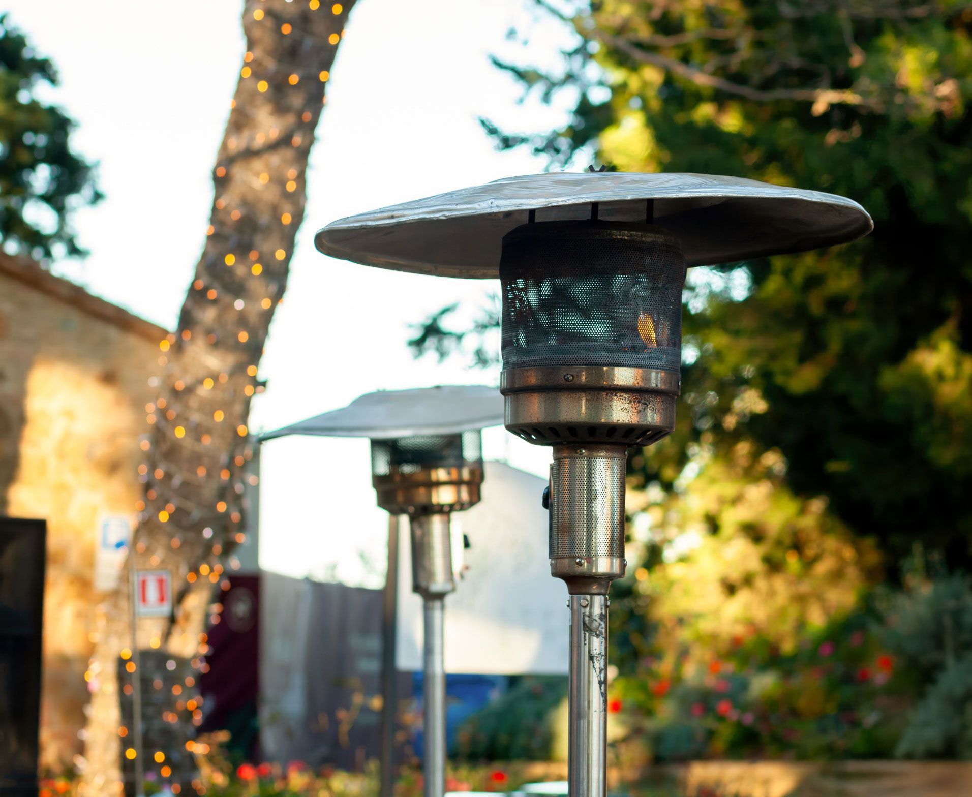 A patio heater is sitting in front of a tree.