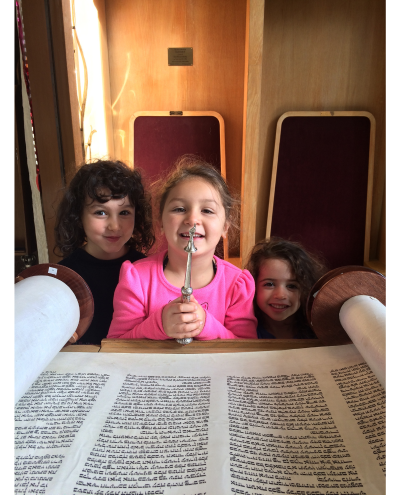 Three young children with a yad and Torah scrll