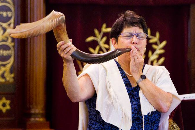 A photo of Rabbi Braun blowing a large shofar