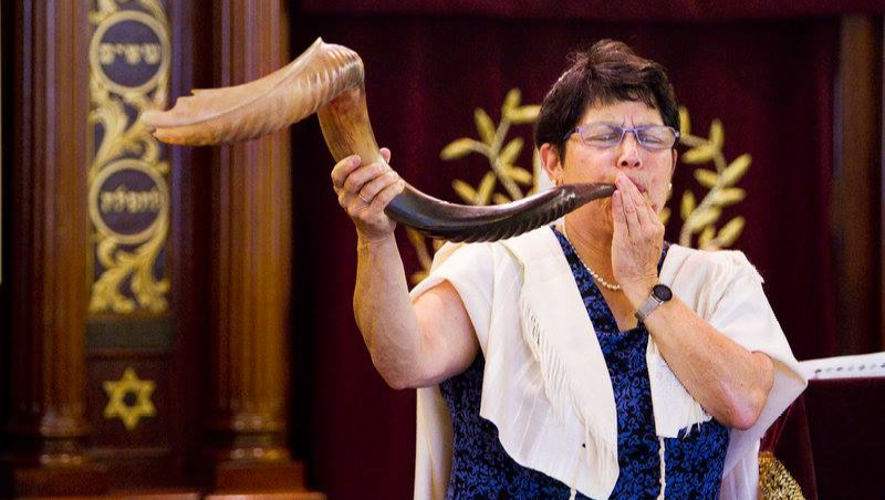 A photo of Rabbi Braun blowing a large shofar
