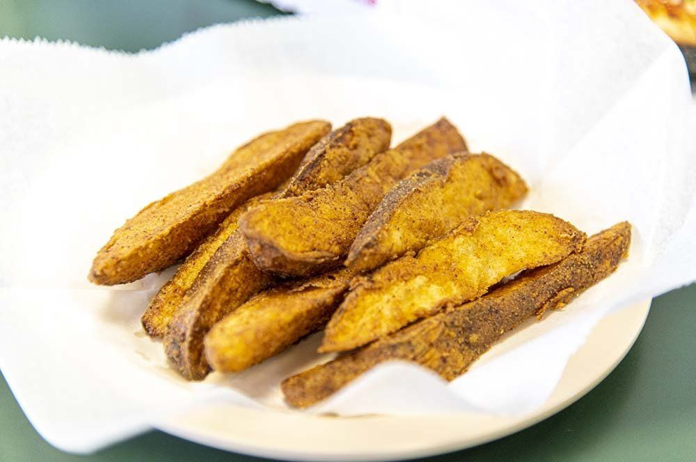 A pile of seasoned potato wedges served on a white paper-lined plate.