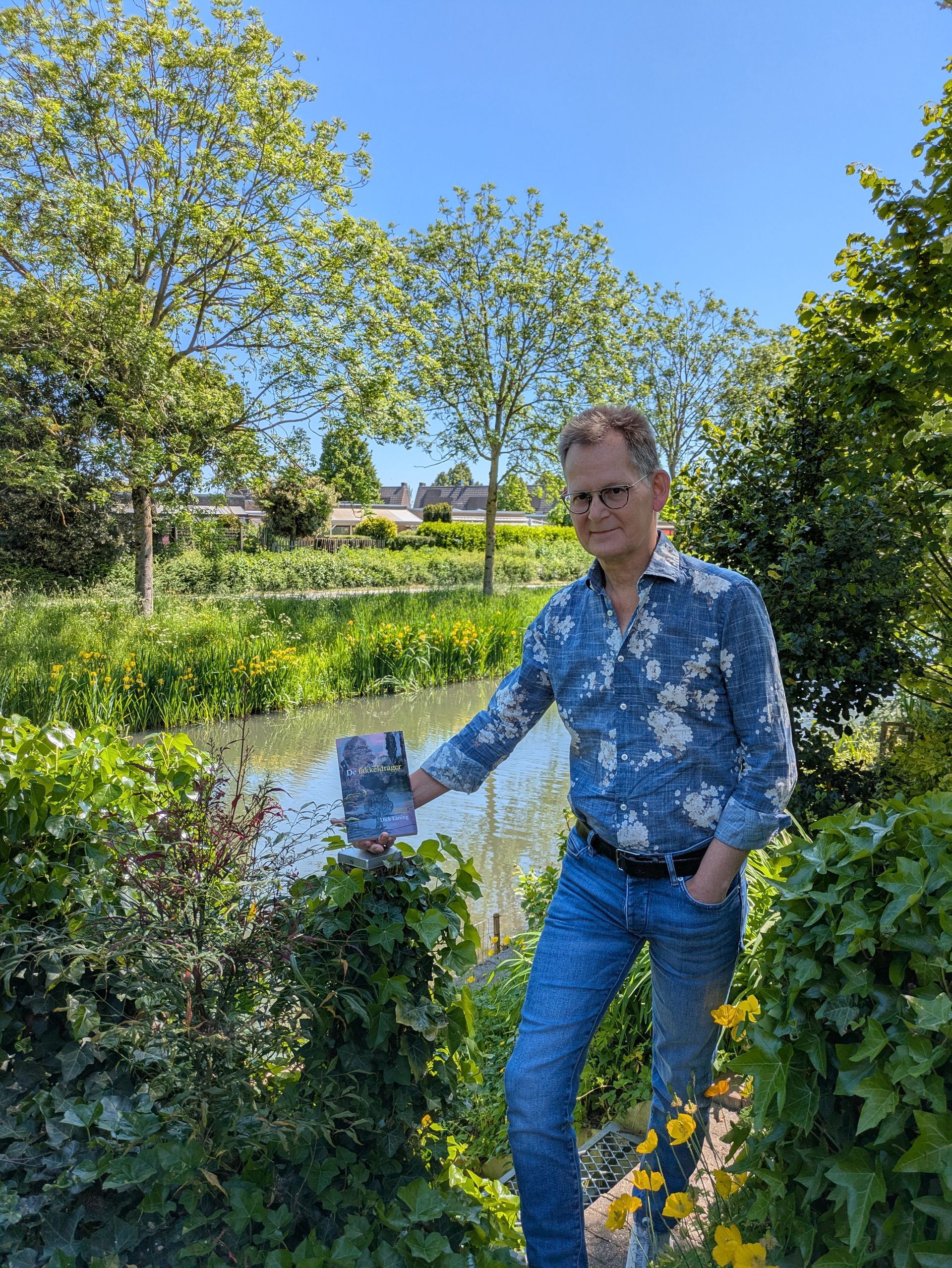 Schrijver Dick Laning toont zijn roman De fakkeldrager voor het water