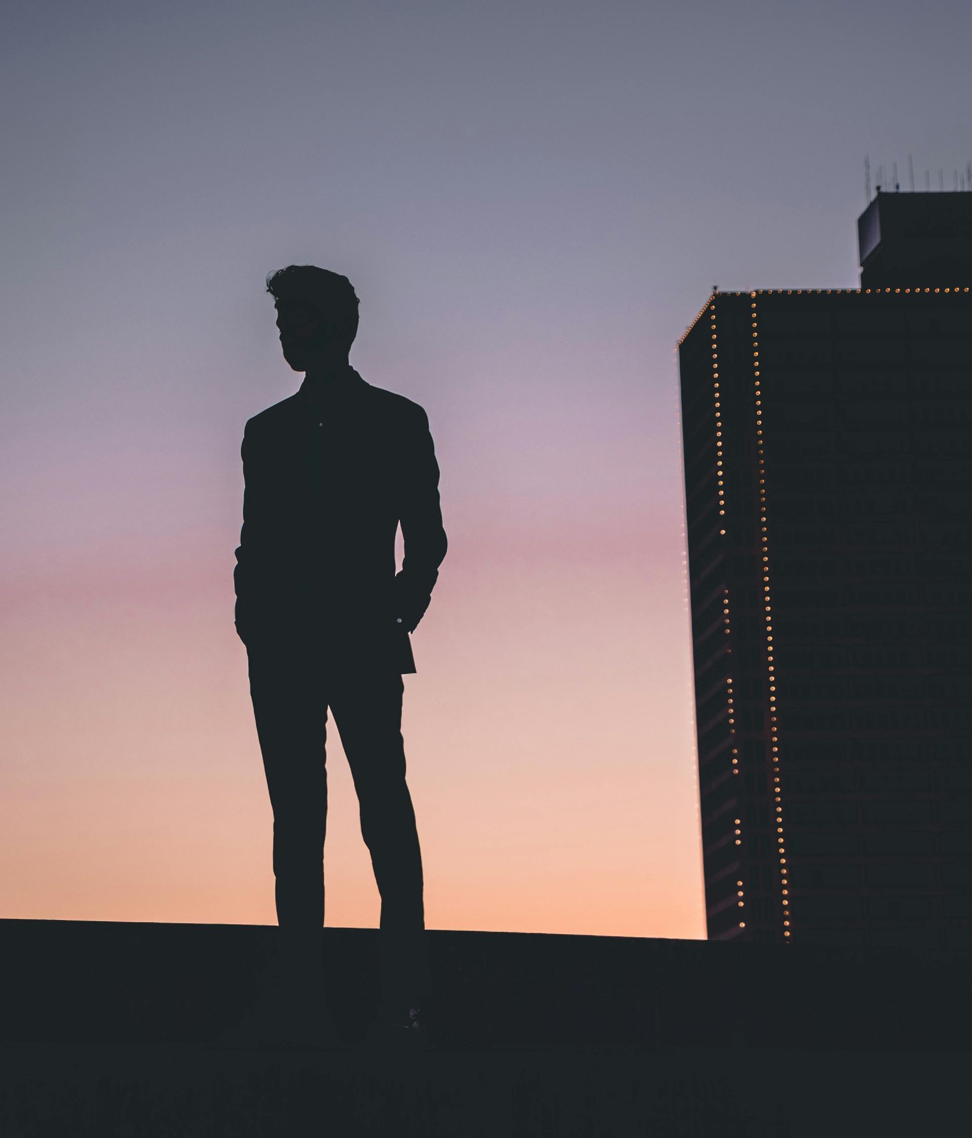 A silhouette of a man standing in front of a Fort Worth building at sunset