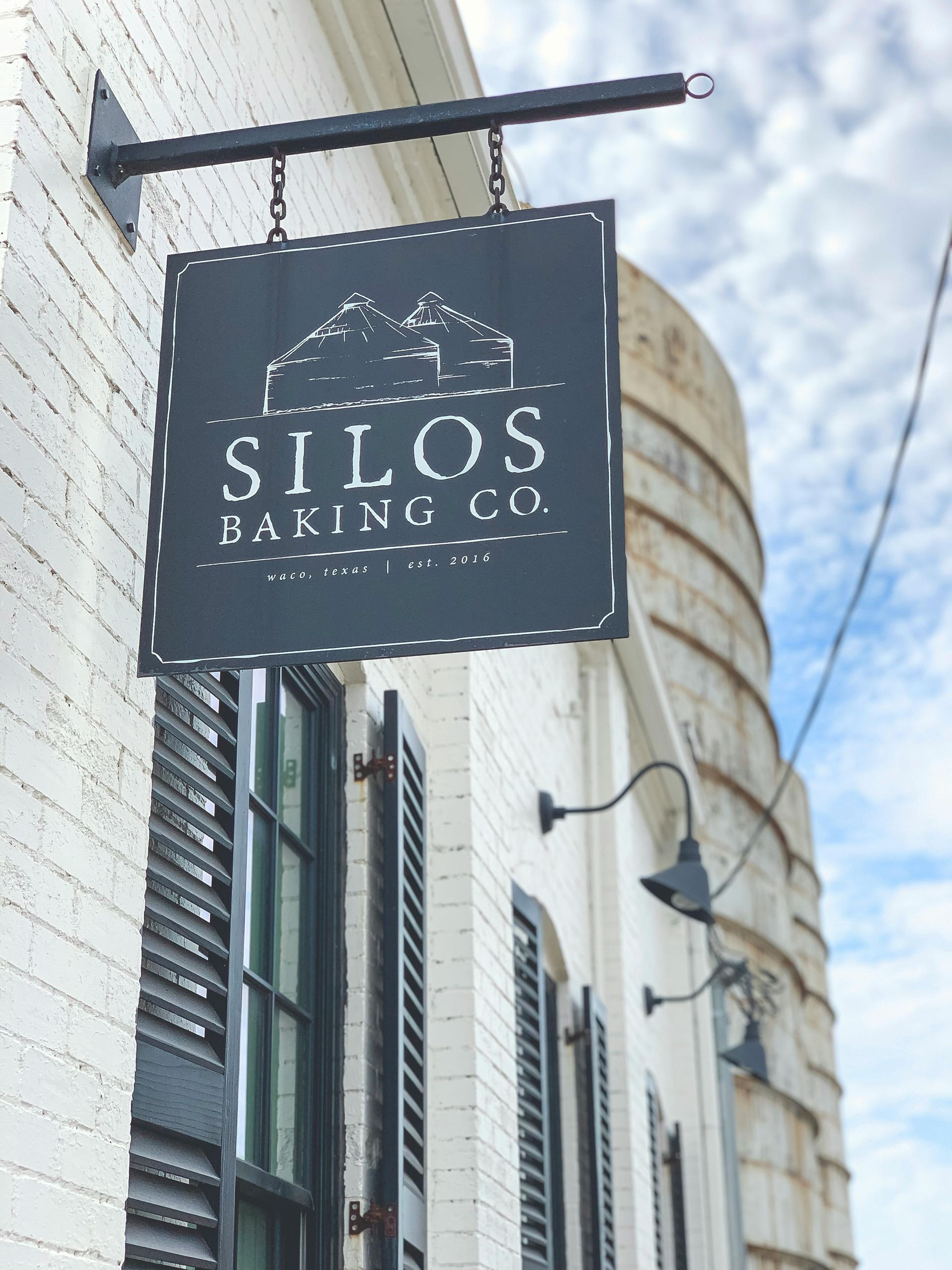 A sign for Silos Baking co. in Waco, Tx hangs from the side of a building