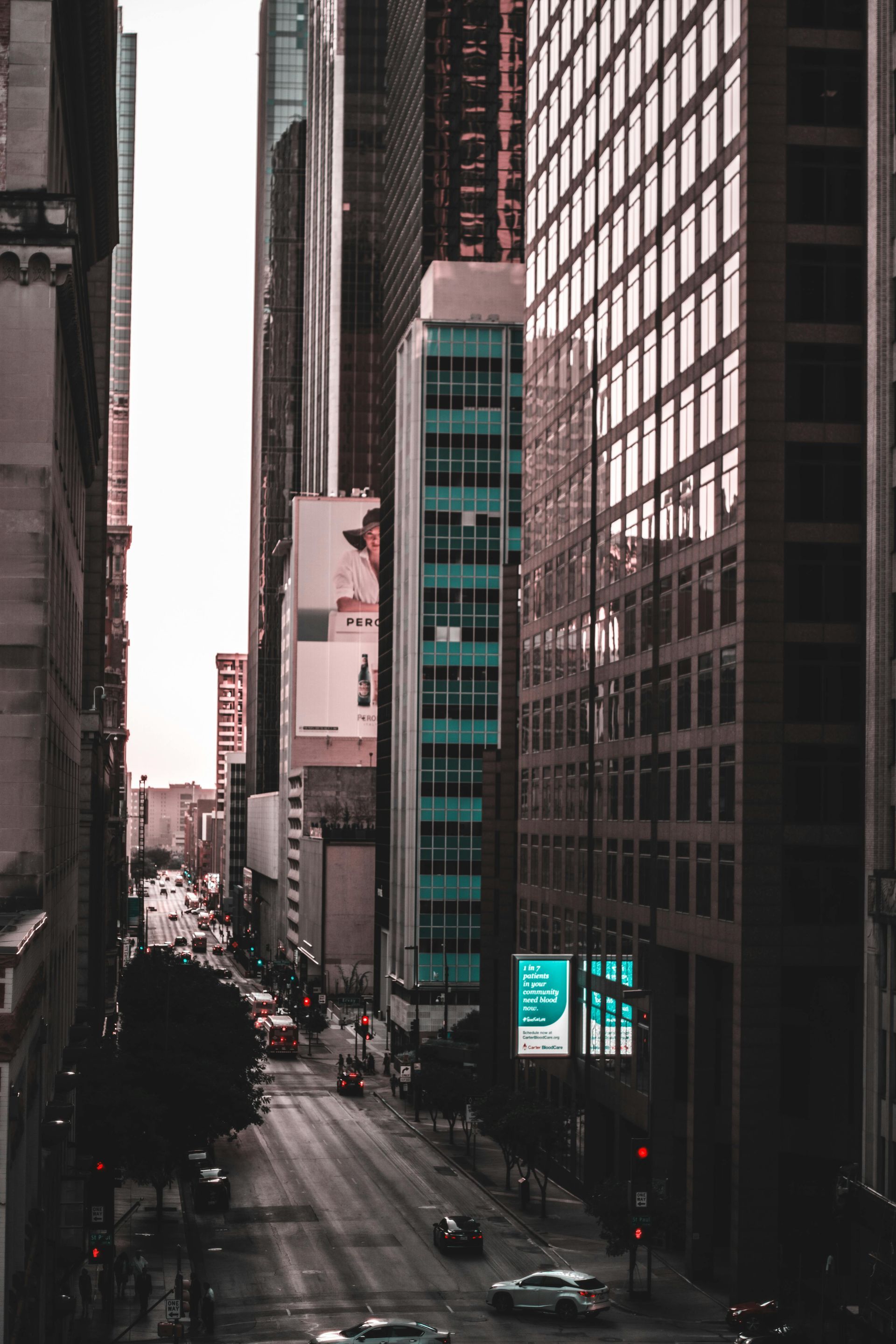 A city street with a lot of tall buildings and cars driving down it in Dallas, Tx
