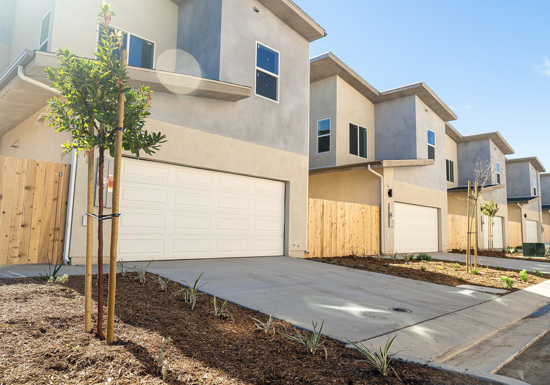 A row of houses with white garage doors and a wooden fence